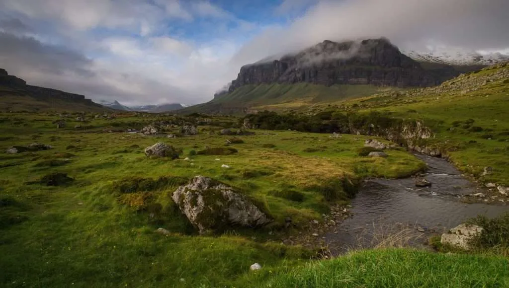 Green grassy valley with a rocky mountain in Ireland.