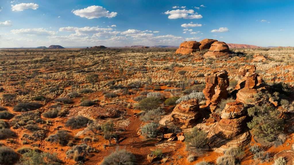 Rocky red desert landscape with sparse shrubs in Australia.