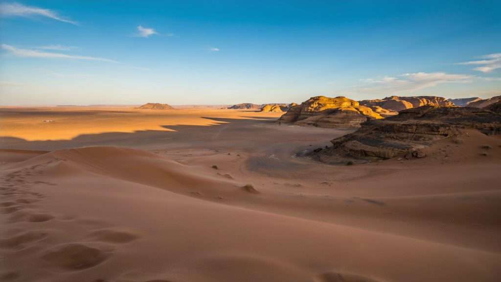 Sand dunes and rocky hills in Chad at sunset.