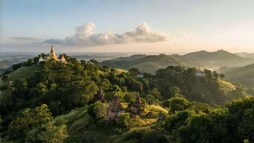 A hilltop pagoda above forested hills in Myanmar.