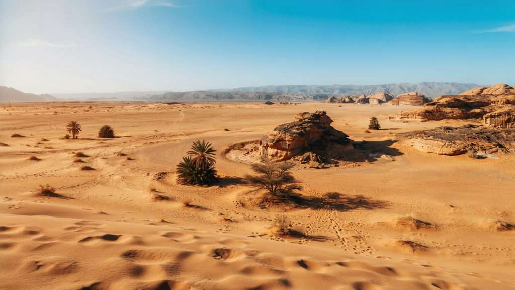 Sand dunes and rocky outcrops in a desert landscape in Saudi Arabia.